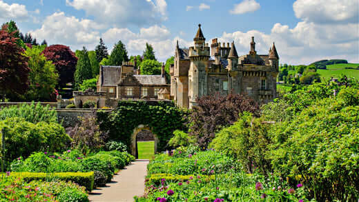 1800s stone castle with ivy-covered turreted walls and formal gardens