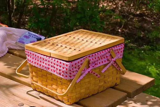 Woven yellow picnic basket with wooden lid and pink bow trim