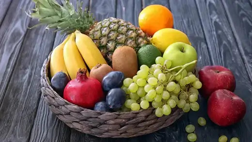 Wicker basket of fresh fruits: bananas, grapes, apples, oranges, kiwis