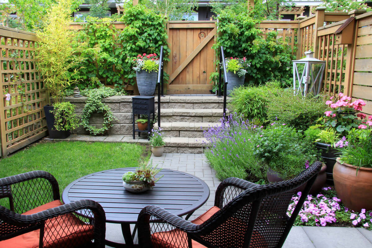 Black wicker patio set with orange cushions in garden design