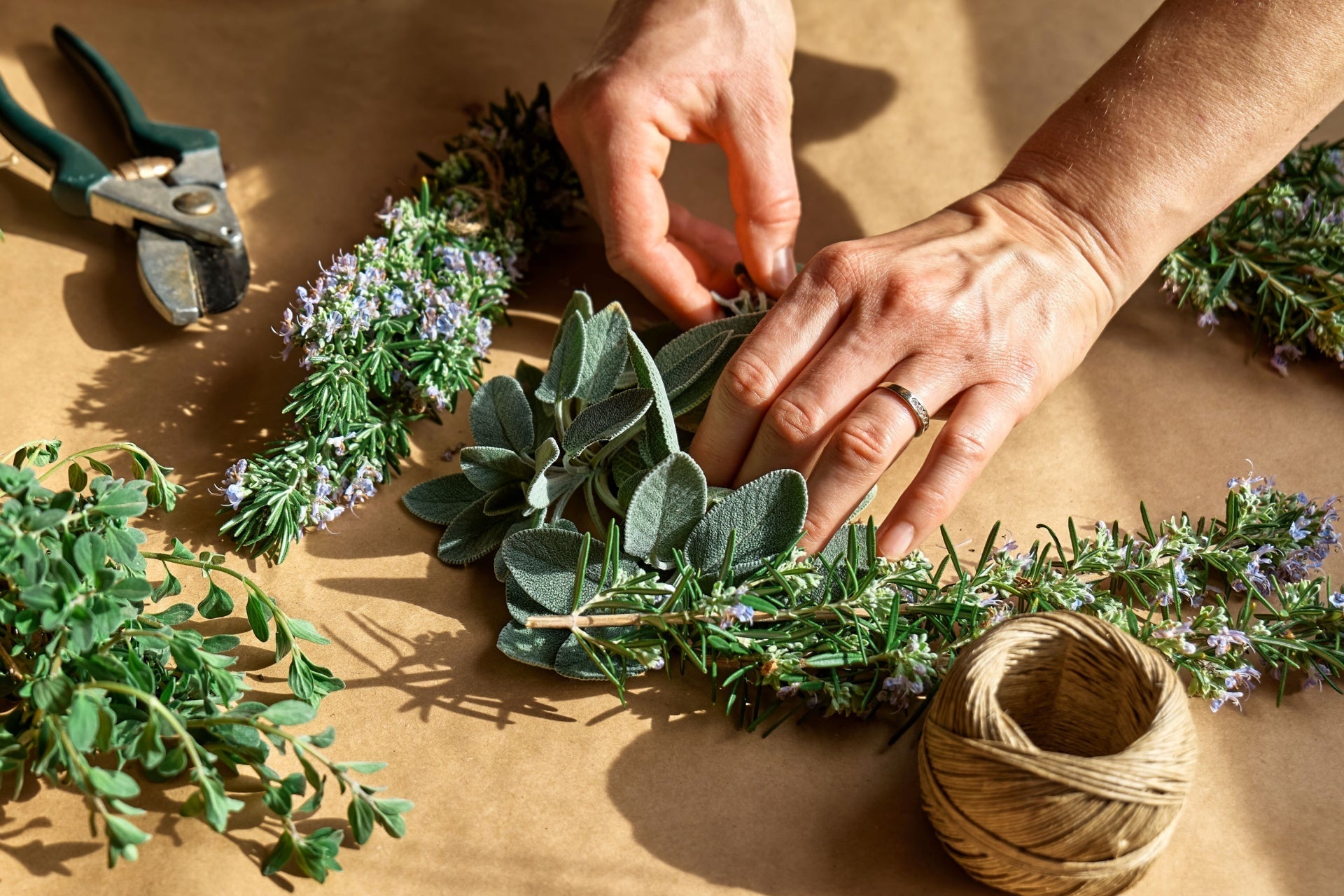 Fresh sage, rosemary, thyme bundle with purple flowers on brown surface