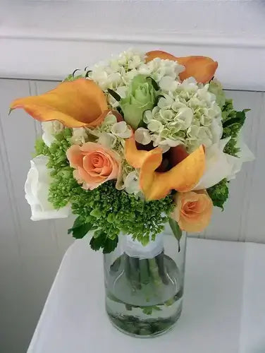Easy orange calla lilies, peach roses, white hydrangeas in glass vase