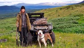 Rugged olive-green off-grid ATV with roof rack in grassy field