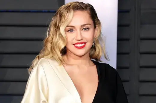 Miley Cyrus in black cream satin two-piece with draped sleeves, Nashville style