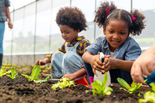 Young girl with pigtails sprays plants while gardening with children