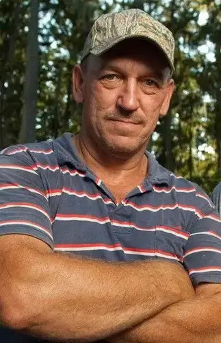 Troy Landry of Swamp People in camo cap and striped polo shirt