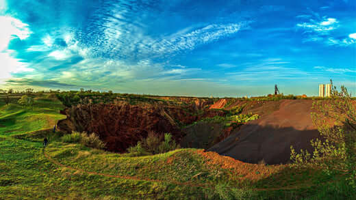 Open-pit mine showing soil erosion risks in rugged terrain under blue sky