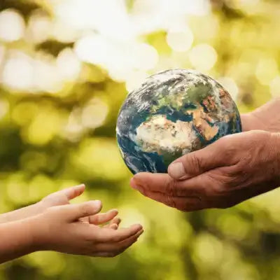 Hands holding detailed globe model highlighting ecological restoration benefits