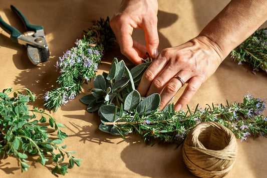 Fresh sage, rosemary, thyme bundle with purple flowers on brown surface