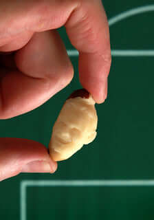 Hand holding creamy white chocolate egg candy with dark brown tip
