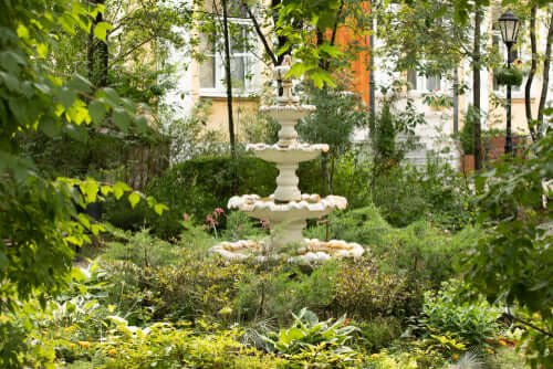 White three-tiered stone fountain with floral accents in garden revival