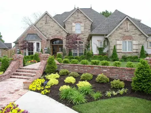 Stone-faced two-story house with gray shingles in stagnant water area